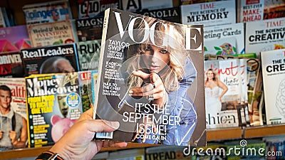 Hand holding a copy of Vogue magazine with Taylor Swift on cover Editorial Stock Photo