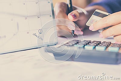 Hand holding credit card calculating her monthly expenses with deadline calendar Stock Photo