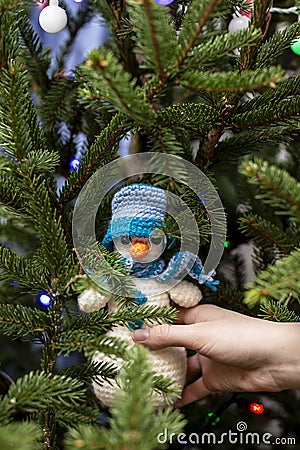 Hand is holding a cute knitted snowman in a hat and scarf on the Stock Photo