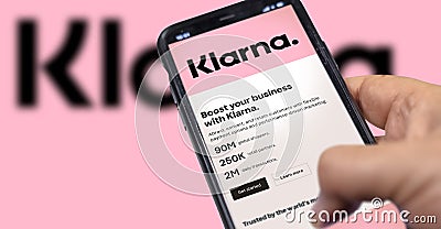 Hand holding a device with the Klarna mobile app on the screen Editorial Stock Photo