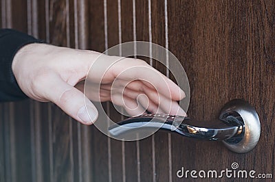 The hand is holding the doorknob. Opens the door. Stock Photo