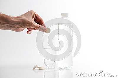 A hand holding effervescent vitamin C is placed in a glass of water Stock Photo