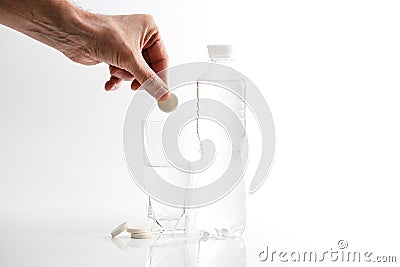 A hand holding effervescent vitamin C is placed in a glass of water Stock Photo