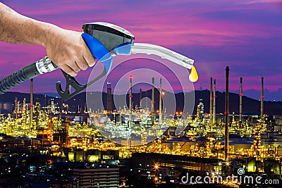 Hand holding a fuel nozzle with refinery background Stock Photo
