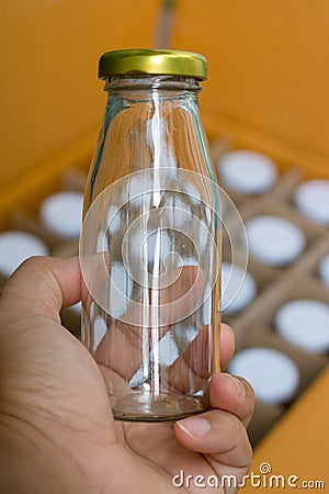 The hand holding a glass bottle with gold bottle caps in a cardboard box, Packaging concept. Stock Photo