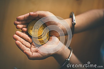 Hand holding golden Bitcoin. Criminal man with handcuffs after committed a crime Stock Photo