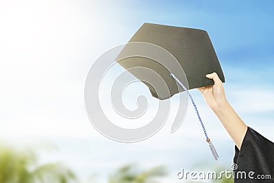 Hand holding graduation hat with blue sky background Stock Photo