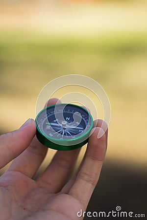 Hand Holding Green Compass Pointing West Stock Photo