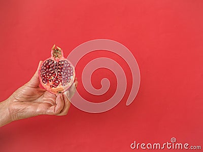 Hand holding half pomegranate on red with copy space Stock Photo