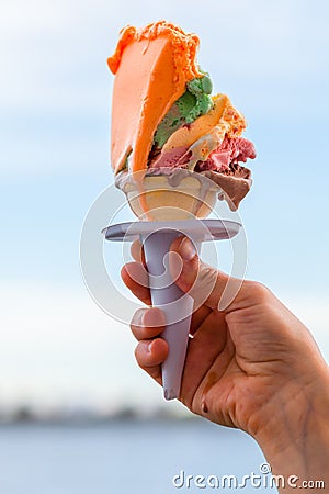 Hand holding ice cream cone with several layers of different colors Stock Photo