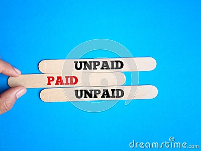 Hand holding a ice cream stick with text Paid and two ice cream stick with text Unpaid. Stock Photo