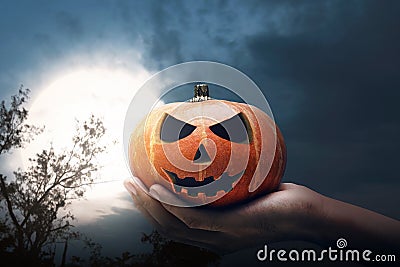 Hand holding Jack-o-lantern with a full moon Stock Photo