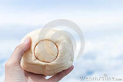 The hand holding Japanese bun over the clouds and blue sky Stock Photo