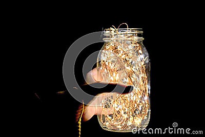Hand Holding a Jar of Bright Fairy Lights Stock Photo