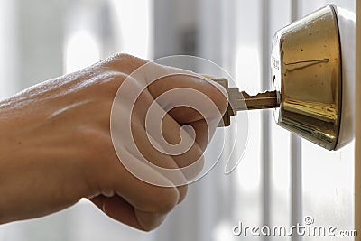 Hand Holding Key in Dead Bolt Lock Close Up Stock Photo