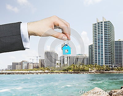 A hand is holding a key from the new home. A concept of real estate property agency. Stock Photo