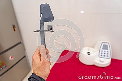 hand holding kitchen robot spatula with respective machine in background. Stock Photo
