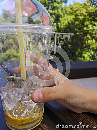 Hand holding lemonade plastic cup with straw. Stock Photo