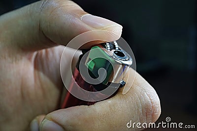 Hand holding lighter to ignite on dark background, Portable device used to create a flame, Close up. Stock Photo