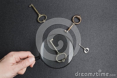 Hand holding magnifier and searching for best key to get success.Key as a sign of great choice Stock Photo