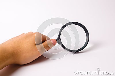 A hand is holding a magnifying glass against a white background. Find information and things, special search capabilities. Stock Photo