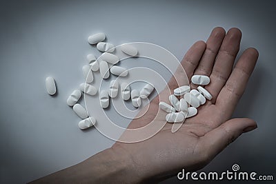 Hand holding many white prescription drugs, medicine tablets or vitamin pills in a pile - Concept of healthcare, opioids addiction Stock Photo