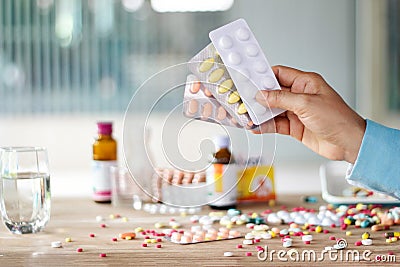 Hand holding medicines pill pack with colorful drugs spread on Stock Photo