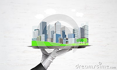 Hand holding metal tray with modern city model against wooden background Stock Photo