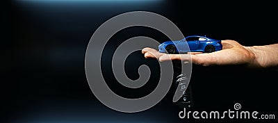 hand holding miniature automobile model and key on dark background. car buying and rental. banner Stock Photo