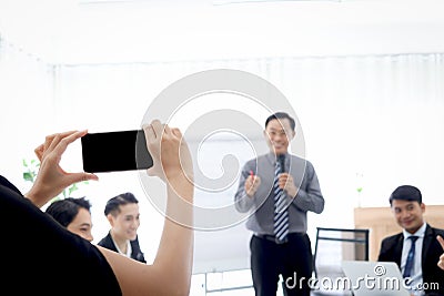 Hand holding mobile phone for taking photo or VDO of business discussing conference with blurred background of brainstorming Stock Photo