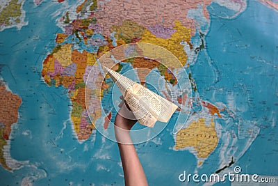 hand holding a paper airplane on the background of the world map. Stock Photo