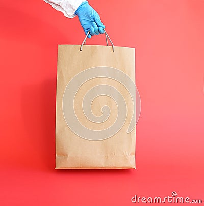 Hand holding a paper bag on a red, isolated Stock Photo
