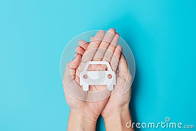 Hand holding paper Car cutout on blue background. Vehicle insurance, warranty, Automobile rental, Transportation, Maintenance and Stock Photo