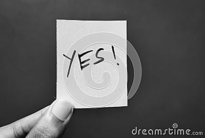 Hand holding a paper card with the word YES. Stock Photo