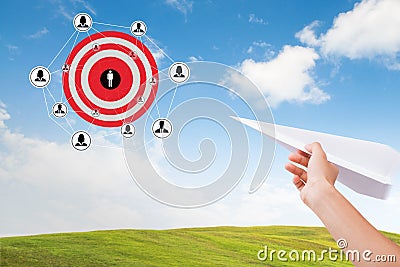 Hand holding paper plane with marketing goals dartboard on sky. Stock Photo