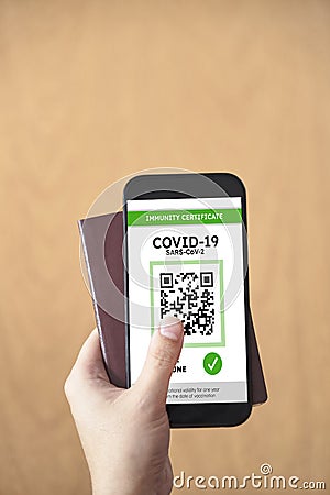 Hand holding a passport and a smartphone with a Covid19 immunity certificate Stock Photo