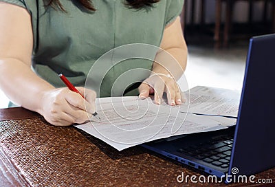 Hand holding pen marking on paperwork in office Stock Photo