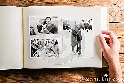 Hand holding photo album with pictures of senior couple. Studio Stock Photo