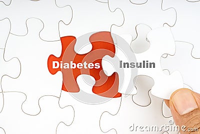 Hand holding piece of jigsaw puzzle with word DIABETES INSULIN Stock Photo