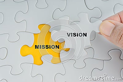 Hand holding piece of jigsaw puzzle with word VISION MISSION Stock Photo