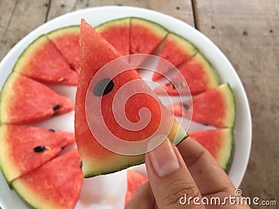 Hand holding a piece of sliced ripe watermelon, top view. Stock Photo