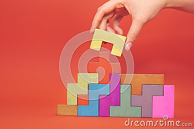 Hand holding piece of wooden block puzzle. wood cube stacking. Concept of complex and smart logical thinking. Slightly Stock Photo
