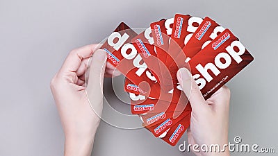 Hand holding pile of Costco wholesale red color gift cards on grey background. Shopping, gift card, shop. Gatineau QC Canada - Editorial Stock Photo