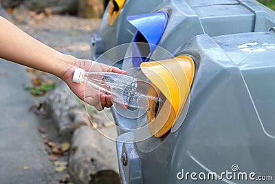 Hand holding plastic bottle and throwing into the garbage for recycle Stock Photo