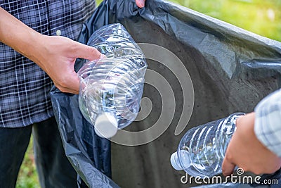 Hand holding plastic bottles waste, Couple picking up trash putting to the black garbage bag at Sunflower Park on Environmental Stock Photo