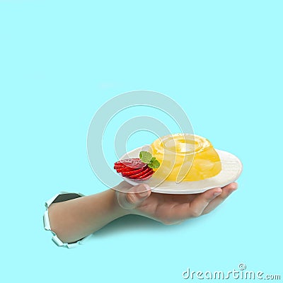 Hand is holding plate of pineapple jelly through torn paper Stock Photo