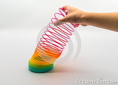Hand holding Rainbow Slinky spring toy isolated on white Editorial Stock Photo