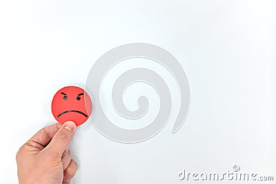 Hand holding a red angry emoticon in white background with copy space. Anger management and bad customer service. Stock Photo