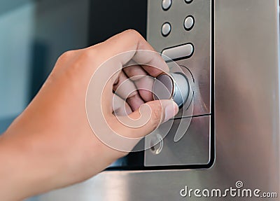 Hand holding rotate dial circle button heat of microwave oven for cooking Stock Photo