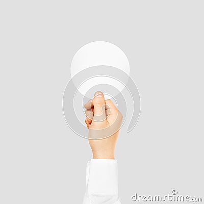 Hand holding round blank white sticker mock up isolated on gray. Stock Photo